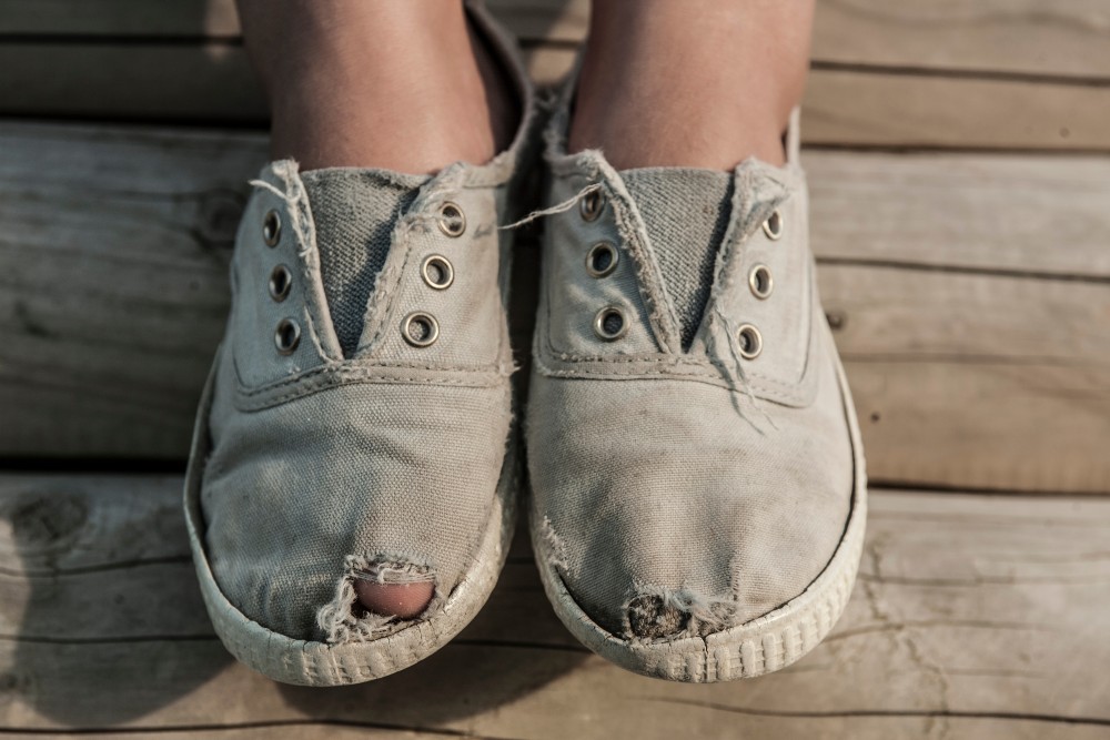 Kid wearing old worn shoes with holes